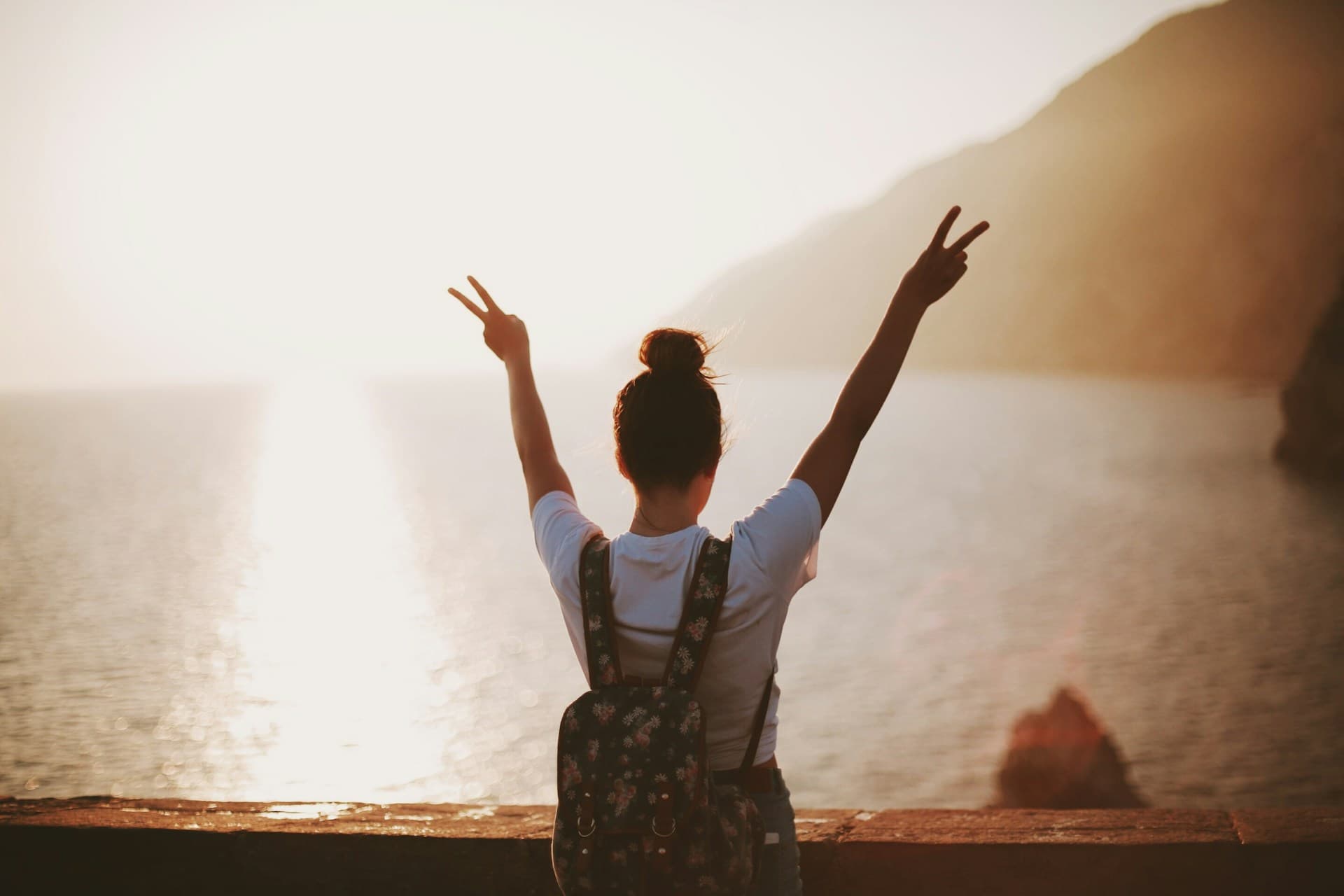 Am I over my ex? Woman looking at the ocean in freedom with peace signs.