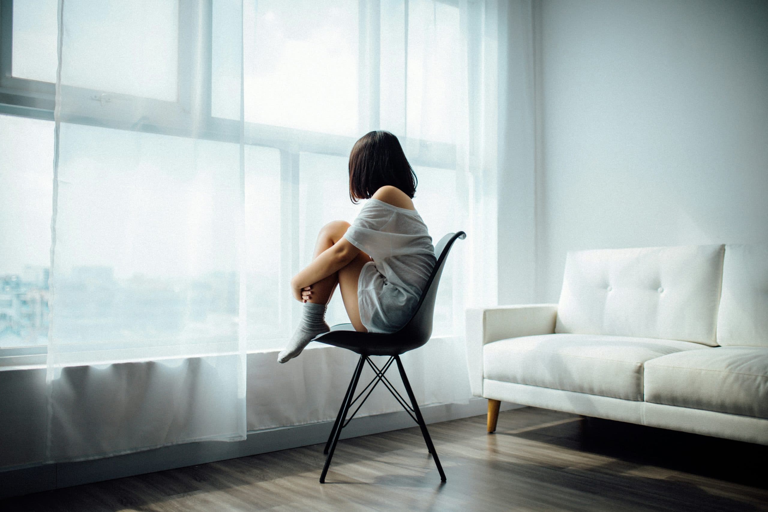 Person sitting and looking lonely in front of window